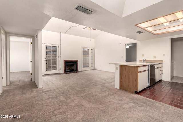 kitchen featuring sink, dark colored carpet, a brick fireplace, dishwasher, and ceiling fan