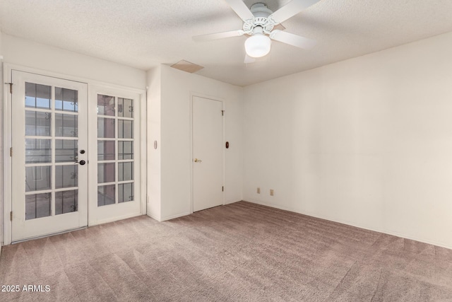 carpeted empty room with ceiling fan, french doors, and a textured ceiling