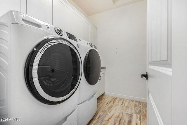 laundry room with cabinets, light hardwood / wood-style floors, and washer and clothes dryer