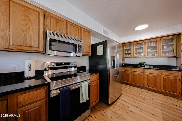 37414 N 17th Ave, Phoenix, AZ 85086 - kitchen with stainless steel appliances, light wood-style flooring, brown cabinetry, glass insert cabinets, and a textured ceiling
