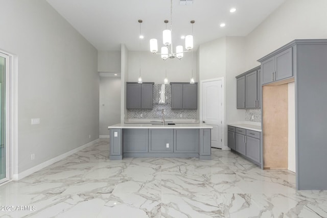 kitchen with gray cabinets, decorative backsplash, a towering ceiling, and light countertops