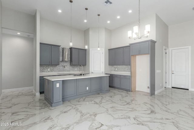 kitchen featuring an inviting chandelier, wall chimney range hood, visible vents, light countertops, and gray cabinetry