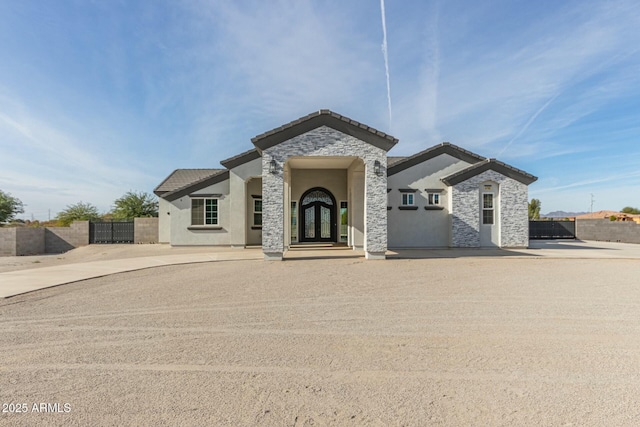 view of front of property featuring a tiled roof, french doors, fence, and stucco siding