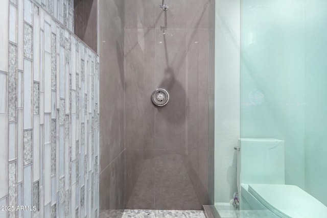 bathroom with a tile shower and toilet