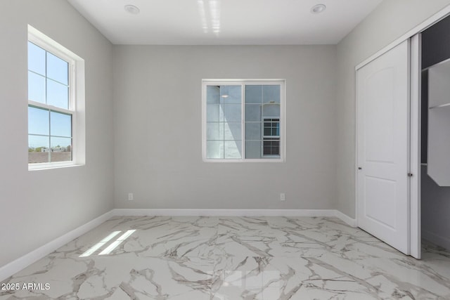 unfurnished bedroom featuring baseboards and marble finish floor