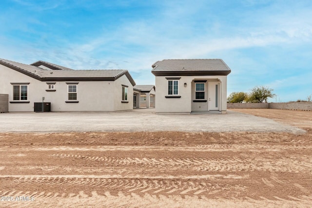 rear view of house featuring a patio, a tiled roof, stucco siding, and central AC