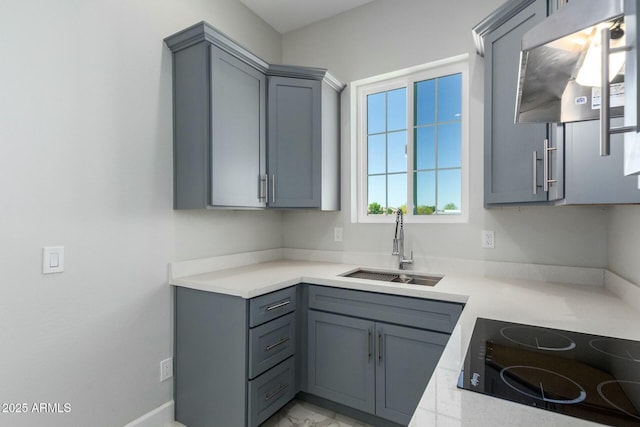 kitchen featuring gray cabinets, a sink, light countertops, black electric stovetop, and extractor fan