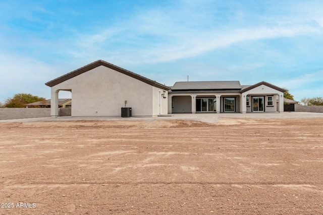 back of house featuring roof mounted solar panels, stucco siding, and central AC unit