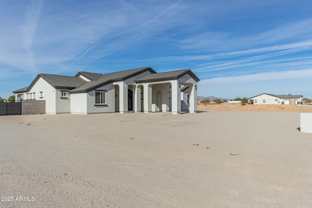 view of front of house with stucco siding and fence