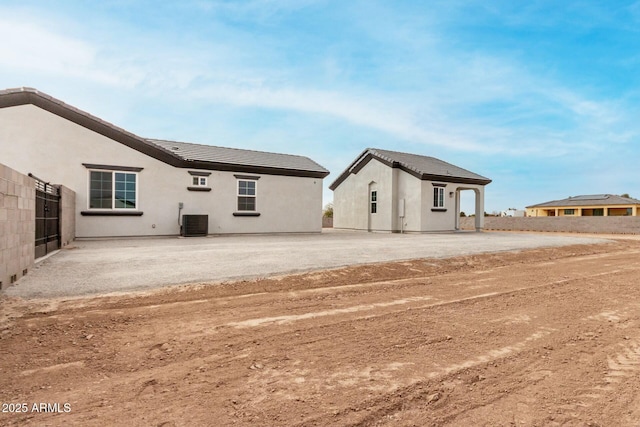 rear view of property with central AC unit, a tile roof, stucco siding, and a patio area