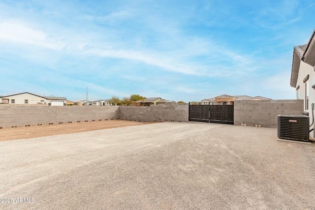 view of yard featuring central AC unit, fence, and a gate