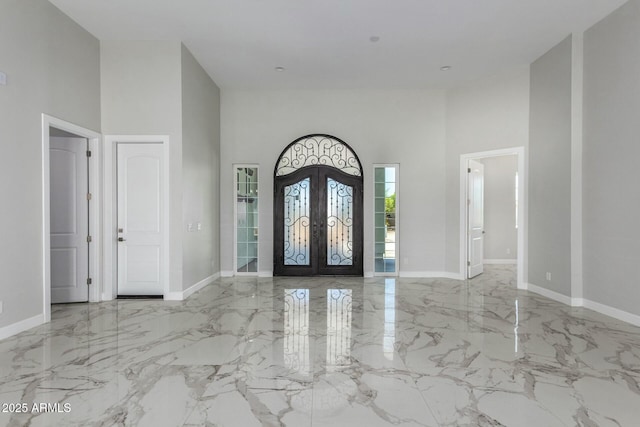 foyer featuring a towering ceiling, french doors, and marble finish floor