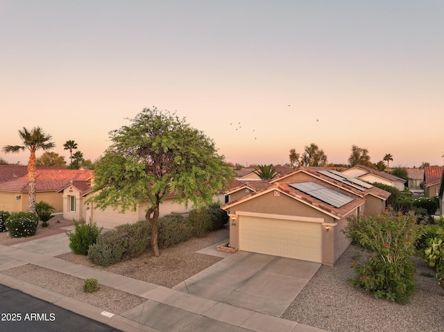 2401 E Antigua Dr, Casa Grande, AZ 85194 - view of front facade featuring stucco siding, driveway, roof mounted solar panels, and a garage