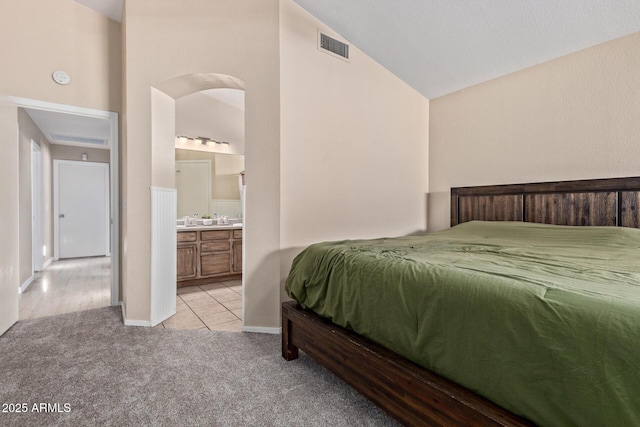 5018 W Wikieup Ln, Glendale, AZ 85308 - bedroom featuring light colored carpet, vaulted ceiling, light tile patterned flooring, and connected bathroom