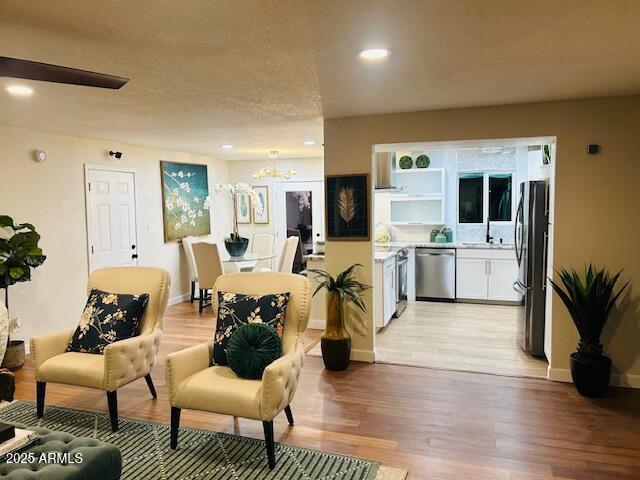 living room featuring a textured ceiling, light hardwood / wood-style floors, and sink