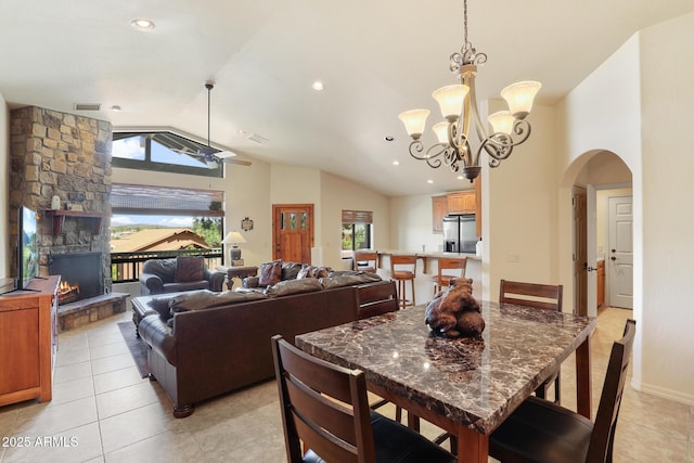 dining area featuring visible vents, arched walkways, lofted ceiling, a fireplace, and light tile patterned flooring