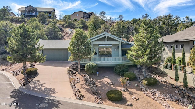 view of front facade with a garage, concrete driveway, a porch, and fence