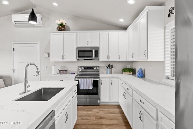 16147 W Apache Way, Peeples Valley, AZ 86332 - kitchen with white cabinets, vaulted ceiling, appliances with stainless steel finishes, a sink, and an AC wall unit