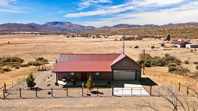 16147 W Apache Way, Peeples Valley, AZ 86332 - view of front of house with a fenced front yard, a garage, metal roof, a mountain view, and driveway