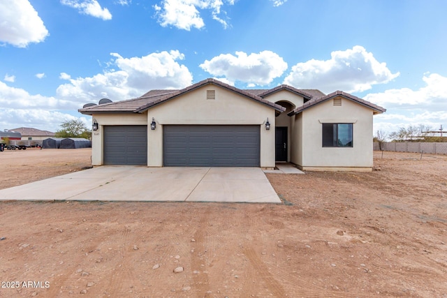 view of front of home with a garage, driveway, fence, and stucco siding