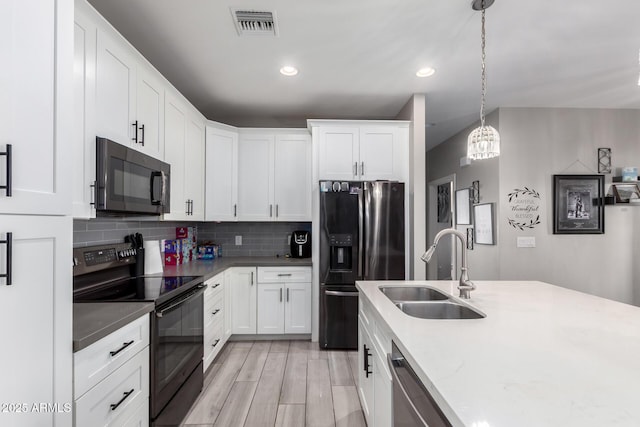 kitchen featuring tasteful backsplash, visible vents, a sink, and black appliances