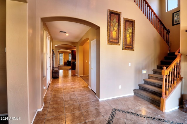 hallway with tile patterned flooring and a towering ceiling