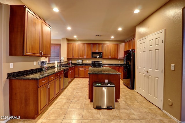 kitchen with sink, dark stone countertops, black appliances, and a center island