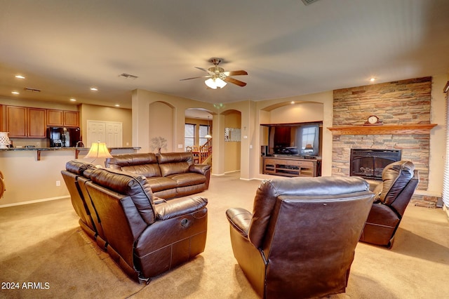 living room with ceiling fan, light colored carpet, and a fireplace