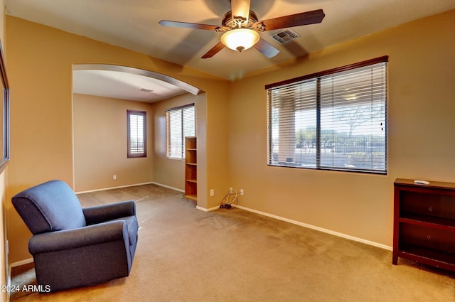 living area with light colored carpet and ceiling fan