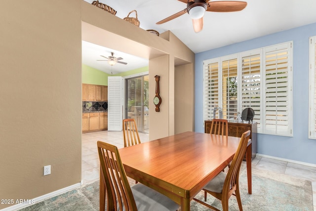 dining area featuring a ceiling fan, vaulted ceiling, baseboards, and light tile patterned floors