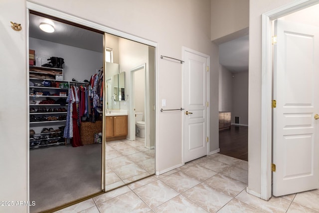 interior space with toilet, a spacious closet, vanity, and tile patterned floors