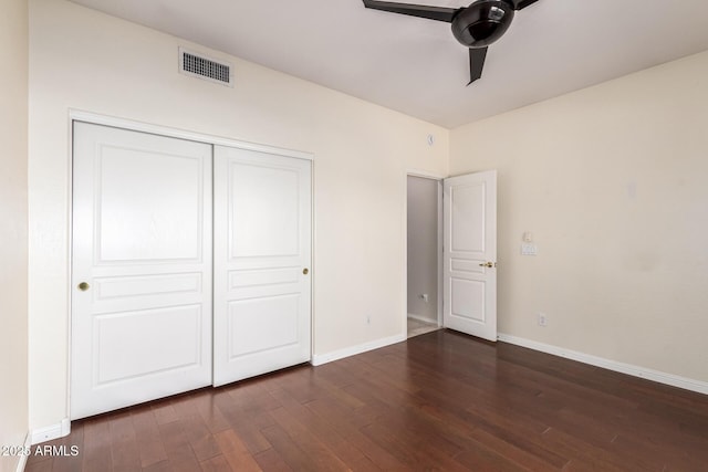 unfurnished bedroom featuring dark wood-type flooring, a ceiling fan, visible vents, baseboards, and a closet