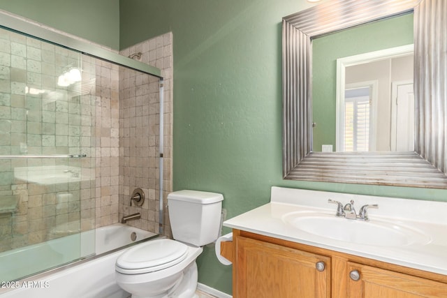 full bathroom featuring toilet, a textured wall, bath / shower combo with glass door, and vanity