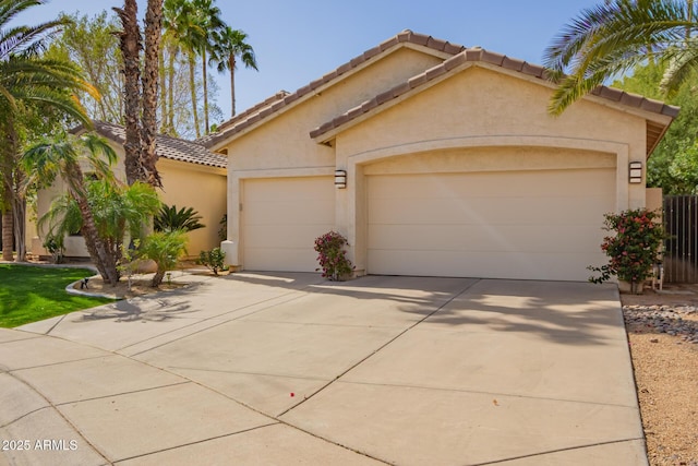 mediterranean / spanish-style house with a garage, driveway, a tiled roof, and stucco siding