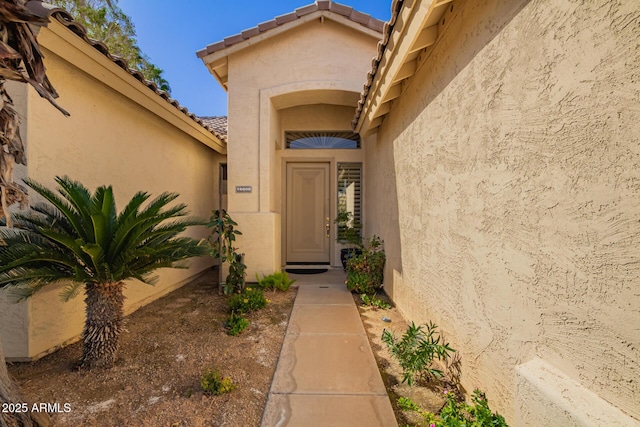 doorway to property with a tiled roof and stucco siding