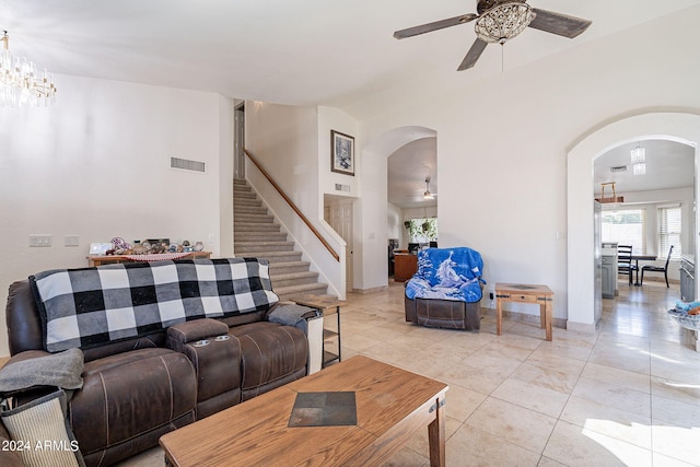 tiled living room with ceiling fan with notable chandelier