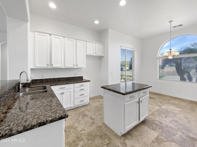 kitchen featuring sink, a notable chandelier, dark stone countertops, white cabinets, and hanging light fixtures