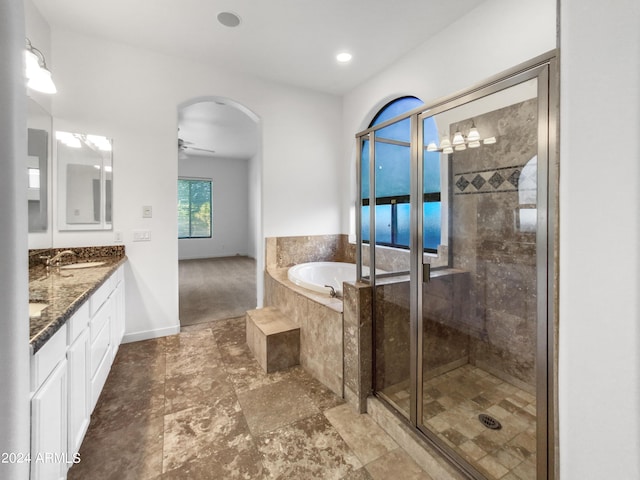 bathroom with ceiling fan, vanity, and plus walk in shower