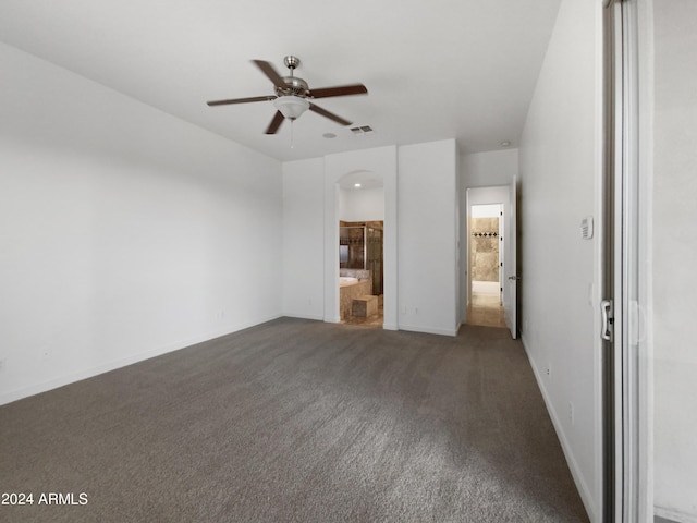 interior space with dark carpet, ensuite bath, and ceiling fan