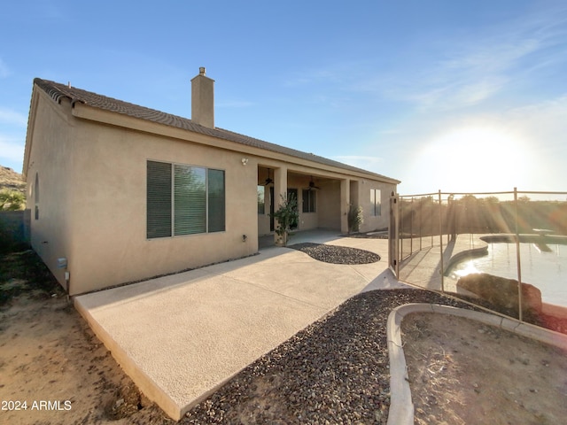 rear view of property with ceiling fan and a patio