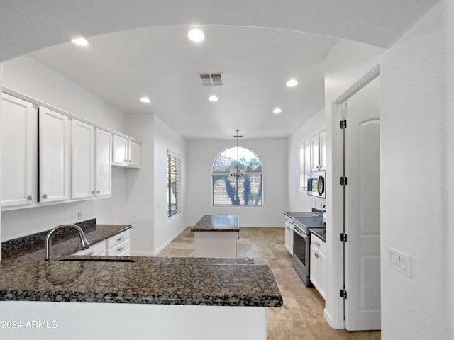 kitchen featuring white cabinets, sink, dark stone countertops, appliances with stainless steel finishes, and decorative light fixtures