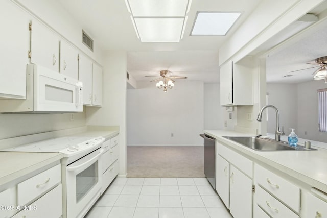 kitchen featuring white appliances, light carpet, sink, a skylight, and white cabinetry