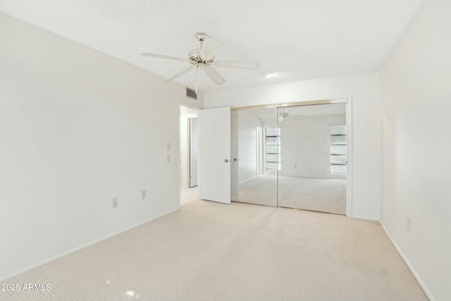 unfurnished bedroom featuring light carpet, a closet, and ceiling fan