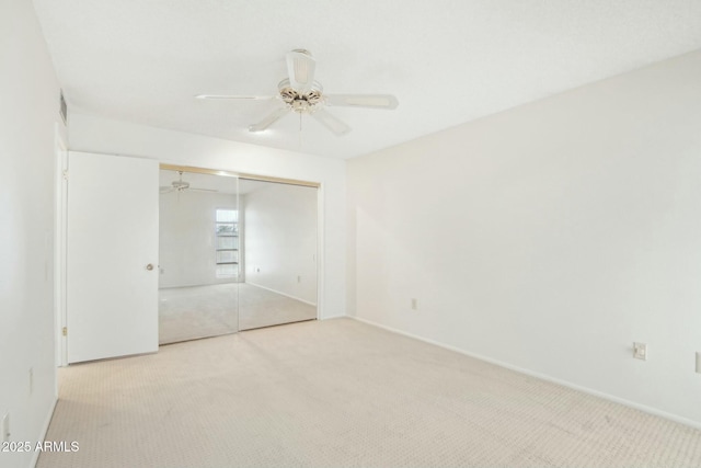 unfurnished bedroom with light colored carpet, a closet, and ceiling fan