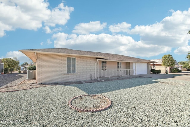 ranch-style home with cooling unit, covered porch, and a garage