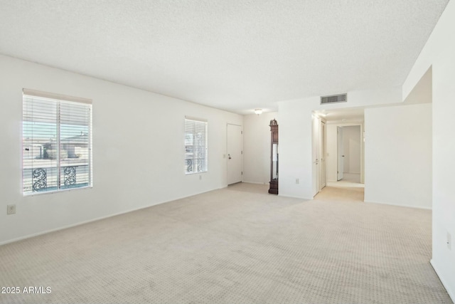 spare room with a textured ceiling and light colored carpet