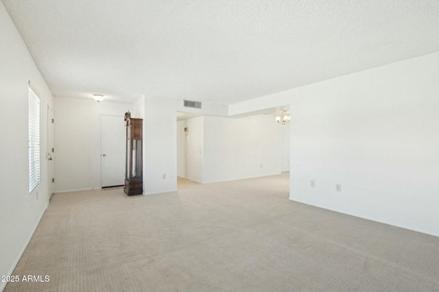 spare room featuring light carpet, plenty of natural light, and a textured ceiling