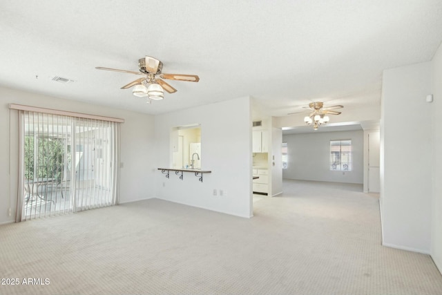 unfurnished living room with a wealth of natural light, light carpet, and ceiling fan