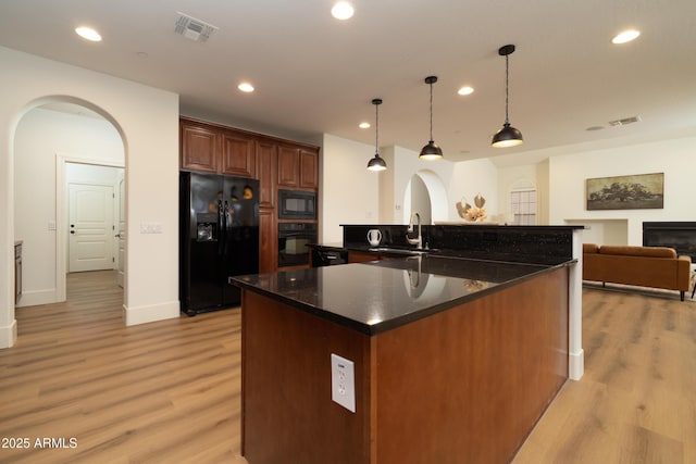 kitchen with black appliances, arched walkways, visible vents, and a spacious island