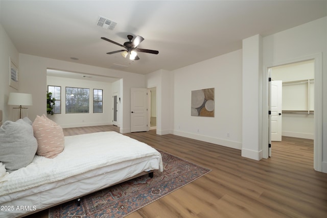 bedroom featuring visible vents, a ceiling fan, baseboards, and wood finished floors